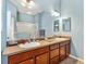 Bathroom boasts double sinks, wood cabinets, and a large mirror at 2304 Jonebury Run, The Villages, FL 32162