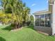 Side yard view showcasing a screened patio and tropical landscaping at 2338 Mcclellanville Ter, The Villages, FL 32162