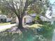 House exterior showcasing a large oak tree and neatly kept lawn at 24947 Cranes Roost Cir, Leesburg, FL 34748