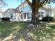 Rear view of a house with a sunroom addition and a large tree at 24947 Cranes Roost Cir, Leesburg, FL 34748