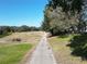 Pathway alongside a golf course, showing lush green grass and trees at 24947 Cranes Roost Cir, Leesburg, FL 34748