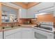 Galley kitchen with white cabinets and electric range at 26409 Evert St, Leesburg, FL 34748