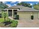 Front view of a single-story house with a three-car garage and mature landscaping at 27238 Stoney Brook Dr, Leesburg, FL 34748