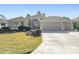 Tan three-car garage home with manicured lawn at 276 Lawthorn St, The Villages, FL 32162