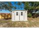 White shed with double doors and windows in the backyard at 3437 Starfish Ave, Fruitland Park, FL 34731