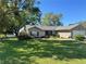 Lovely single-story home featuring a well-manicured lawn, mature trees, and a classic brick facade at 36703 Sandy Ln, Grand Island, FL 32735