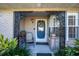 Charming covered entryway with a decorative wrought iron arch and beautiful blue front door at 36703 Sandy Ln, Grand Island, FL 32735