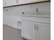 Clean white laundry room with a white sink and storage cabinets, tile floors and white walls at 5095 Firebush Dr, Apopka, FL 32712