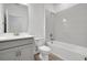 Bright bathroom featuring gray cabinets, white subway tile in shower/tub combo, and wood-look tile flooring at 5131 Firebush Dr, Apopka, FL 32712