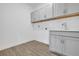 Neat laundry room featuring gray cabinets, utility sink, white walls, and wood-look tile flooring at 5131 Firebush Dr, Apopka, FL 32712