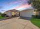 Tan house with white garage door and landscaping at 6220 Topsail Rd, Lady Lake, FL 32159