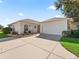 Tan house with white garage door and landscaping at 6220 Topsail Rd, Lady Lake, FL 32159