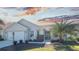 Tan one-story house with attached garage, landscaping, and palm trees at 670 Murphys Estate Dr, The Villages, FL 32162