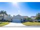 Tan house with a two-car garage and palm trees at 670 Murphys Estate Dr, The Villages, FL 32162