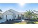 Tan house with a two-car garage and palm trees at 670 Murphys Estate Dr, The Villages, FL 32162