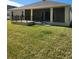 Backyard view of a house with a large screened porch and grassy lawn at 6851 Wendy Way, The Villages, FL 32163