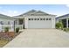 White house with gray roof, two-car garage, and picket fence at 7189 Denver Ave, The Villages, FL 34762