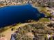 Aerial view of property highlighting lakefront position and wooded area at 73 N Carol Ave, Mascotte, FL 34753