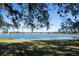 Peaceful lake view from lakeside property with oak trees and blue sky at 73 N Carol Ave, Mascotte, FL 34753