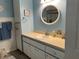 Bathroom with modern vanity, round mirror, and storage; decorated with blue and white accents at 10173 Se 175Th Ln, Summerfield, FL 34491