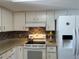 White kitchen with a tiled backsplash and stainless steel appliances at 10173 Se 175Th Ln, Summerfield, FL 34491