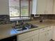 Close-up of a kitchen sink with a window, featuring tile backsplash and bright lighting at 10173 Se 175Th Ln, Summerfield, FL 34491