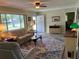 Inviting living room with large window, ceiling fan, plush patterned rug, and comfortable seating arrangement at 10173 Se 175Th Ln, Summerfield, FL 34491