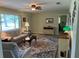 Cozy living room featuring a ceiling fan, a patterned area rug, and a door leading to a room in the back at 10173 Se 175Th Ln, Summerfield, FL 34491