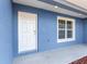 Modern home exterior featuring a blue facade, white door, and a small window at 105 Juniper Run, Ocala, FL 34480