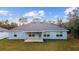 Rear view of a blue single-story home with a covered patio and well-maintained lawn on a sunny day at 15065 Se 93Rd Ave, Summerfield, FL 34491