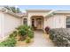 Welcoming front entry with arched entryway, landscaped walkway, and a bench at 1870 Saybrook Way, The Villages, FL 32162