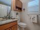 Small bathroom with granite countertop and wood cabinet at 2057 Countrywind Ct, The Villages, FL 32162