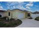 Bright yellow house with a two-car garage and well-manicured landscaping at 2078 Pink Blossom Ct, The Villages, FL 32162