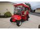 Red golf cart with tan seats and a red top at 2078 Pink Blossom Ct, The Villages, FL 32162