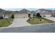 Tan house with landscaped yard, 3-car garage, and paver driveway at 2096 Odessa Cir, The Villages, FL 32162