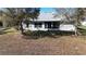 Rear view of a single story home with a screened in porch and a large backyard at 24308 Belle Mede Dr, Leesburg, FL 34748