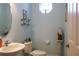 Powder room with light blue walls, oval mirror, pedestal and octagon window above the toilet at 24308 Belle Mede Dr, Leesburg, FL 34748