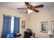 Bedroom featuring a ceiling fan, window with blue curtains and beige walls at 24308 Belle Mede Dr, Leesburg, FL 34748