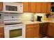 Kitchen with white stove and microwave, oak cabinets, stainless steel dishwasher, and tile backsplash at 24308 Belle Mede Dr, Leesburg, FL 34748