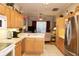 Galley kitchen featuring wood cabinetry, stainless steel appliances, and an open layout to the living room at 24308 Belle Mede Dr, Leesburg, FL 34748