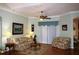 Bright living room with hardwood floors, floral sofas, and a ceiling fan at 24308 Belle Mede Dr, Leesburg, FL 34748