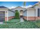 Front entry of a house with brick accents and landscaping at 25220 Waterbridge Ct, Leesburg, FL 34748