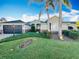 Single-story home with a dark brown garage door, landscaping, and palm trees at 25220 Waterbridge Ct, Leesburg, FL 34748