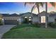 House exterior at dusk with a dark garage door and landscaping at 25220 Waterbridge Ct, Leesburg, FL 34748