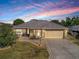 Single-story home with attached garage and manicured lawn at dusk at 307 Batesburg Way, The Villages, FL 32162