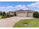 Tan house with a three-car garage, neatly landscaped lawn, and a paved driveway at 3538 Mistletoe Ct, The Villages, FL 32163