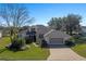 Single-story home with a gray roof, two-car garage, and nicely landscaped yard at 3546 Tropical Seas Loop, Tavares, FL 32778