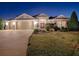 Well-lit home exterior at night showcasing a two-car garage and landscaping at 3590 Ithaca Ter, The Villages, FL 32163