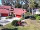 Aerial view of Spanish-style home with red tile roof and lush landscaping at 601 Waterwood Dr, Yalaha, FL 34797