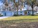 Mid-century modern home with light blue exterior, new garage door, and manicured lawn at 908 N Lakeshore Blvd, Howey In The Hills, FL 34737